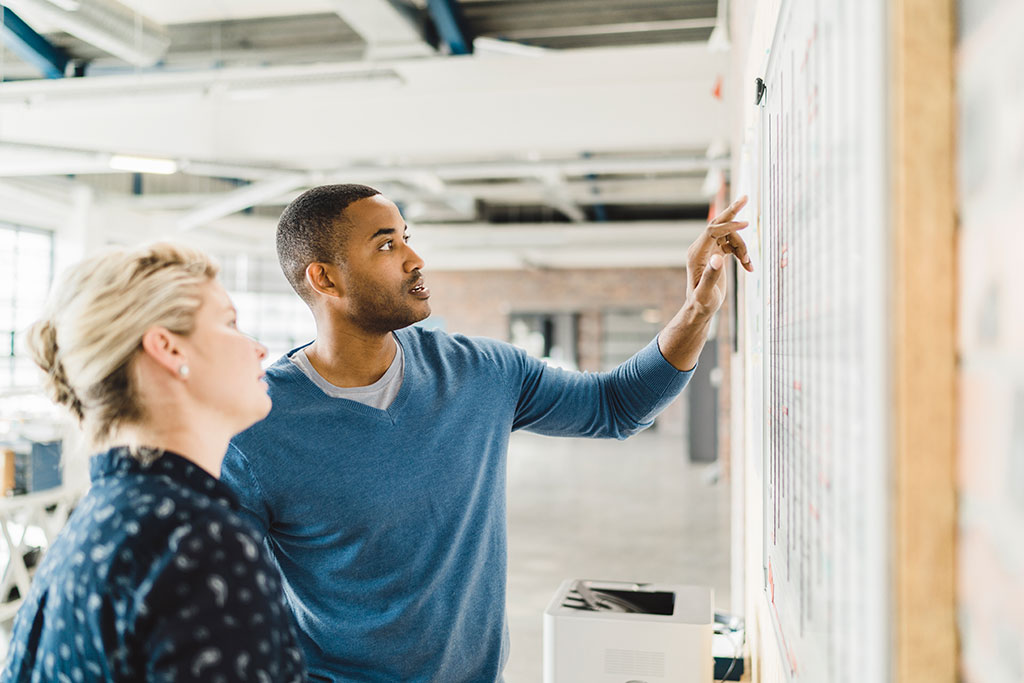 Growth-Minded - image of two people working together on a white board